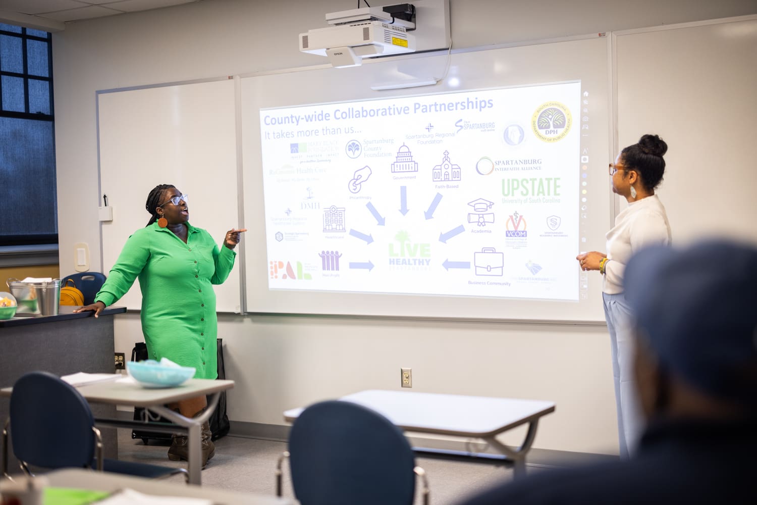 Selena Smith and Erica Rhodes presenting during a workshop, the presentation features a slide about County-wide partnerships. Many of LHS's partners are featured